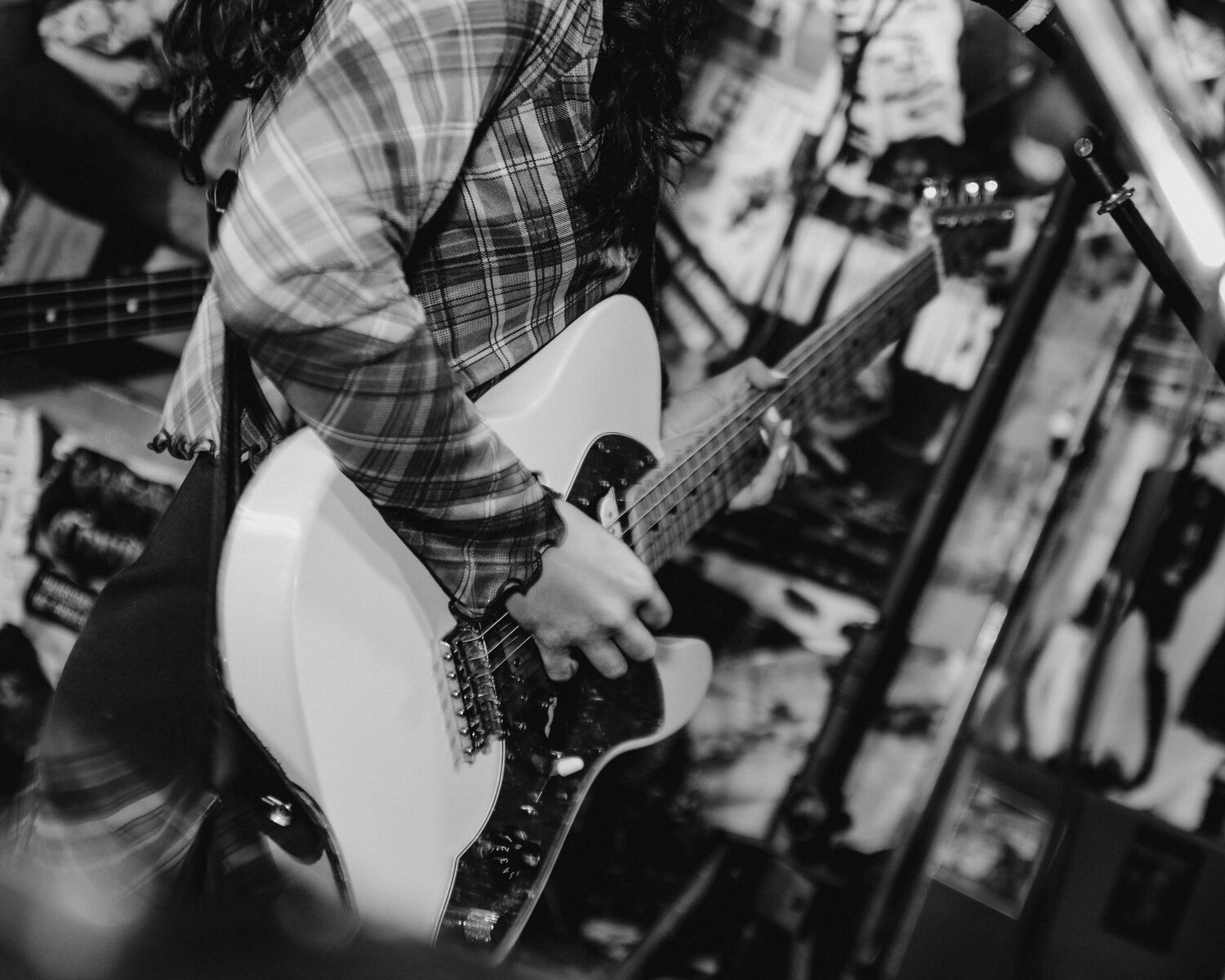Close-up of a guitarist playing an electric guitar at a small live show, in black and white